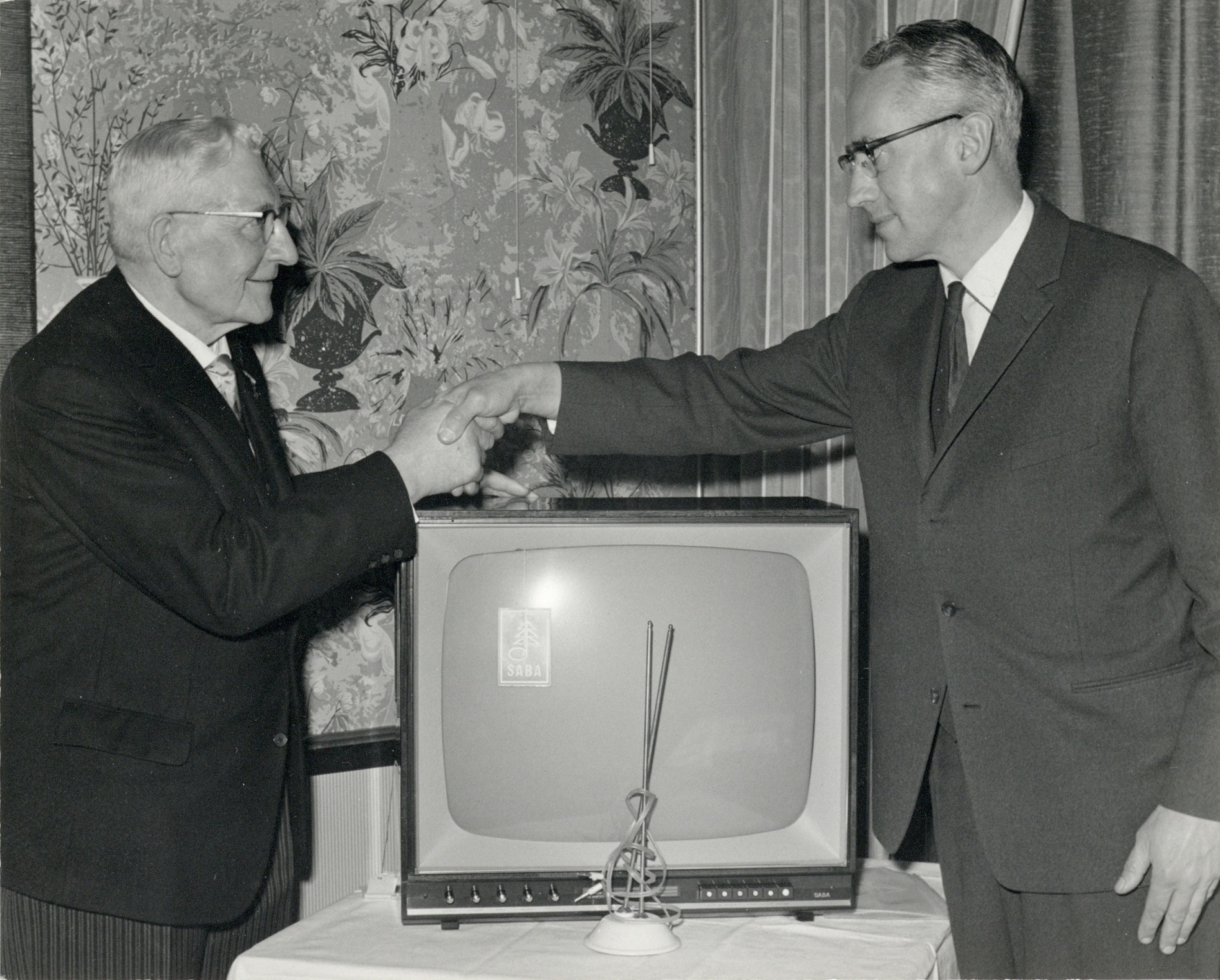 de heer T. van der Scheur ontvangt een televisietoestel van de heer de Beaufort directeur van Grund vanwege zijn 50 jarig dienstverband bij de automobielhandel